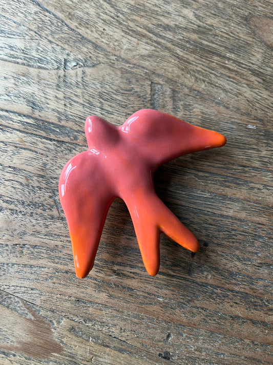 Zwaluw voor aan de muur roze oranje